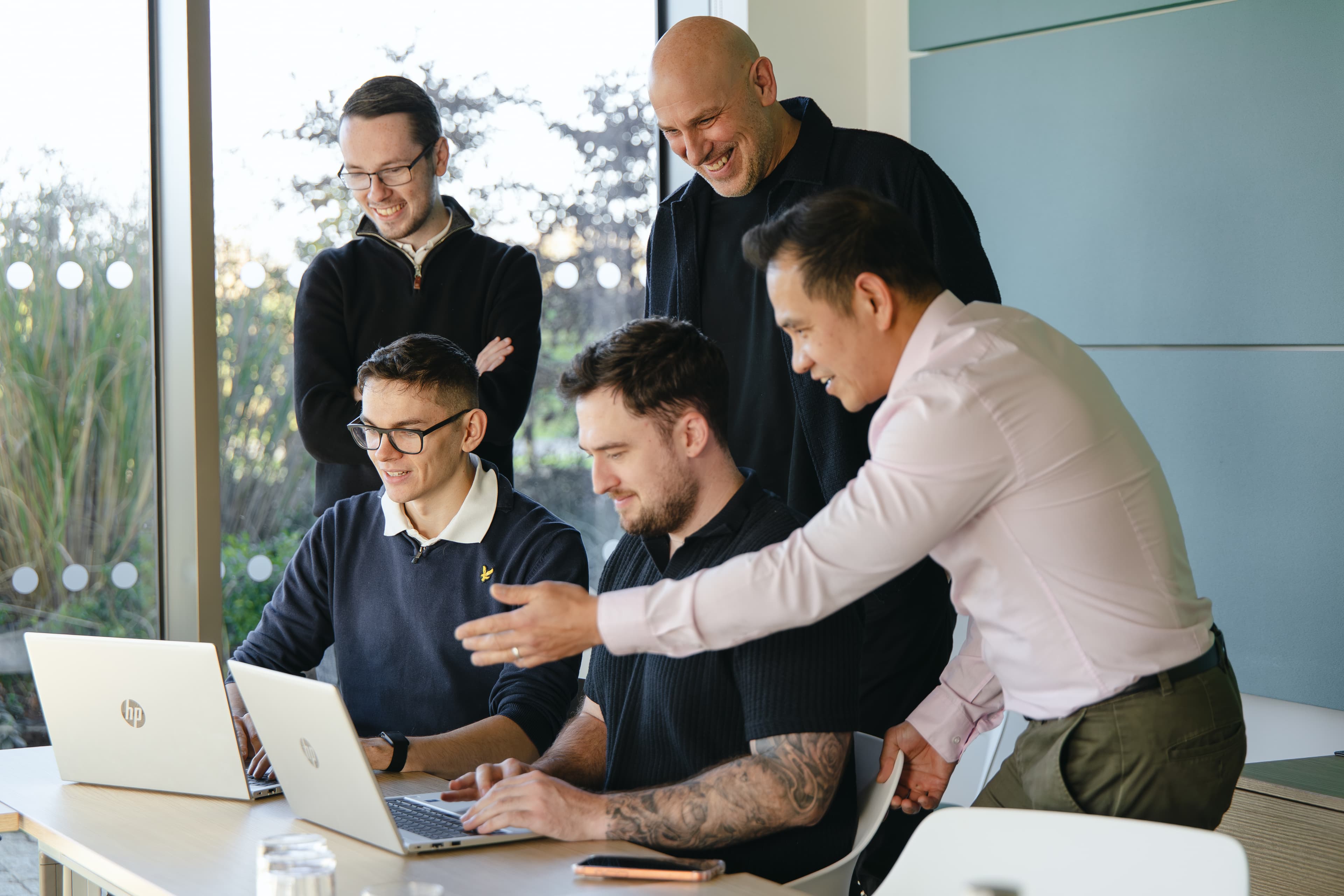Cyber security team collaborating around laptops